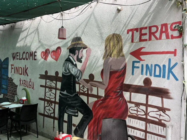 A cafe terrace in Balat with a painted mural along the wall