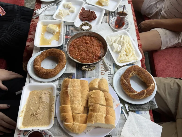 A Turkish breakfast from above: simit, olives, cheeses, kaymak, menemen and glasses of tea