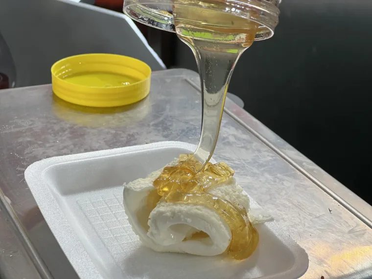 Honey poured over a plate of kaymak, Turkish clotted cream, at a breakfast counter