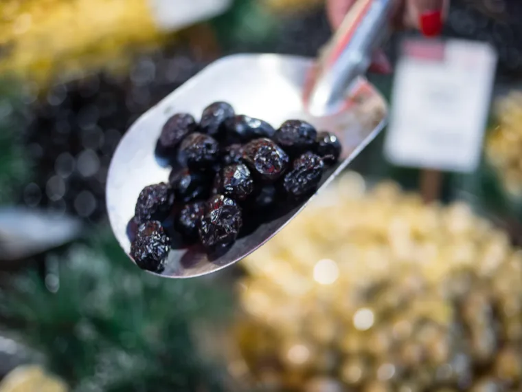 A scoop lifting black olives from the barrel at an Istanbul market stall