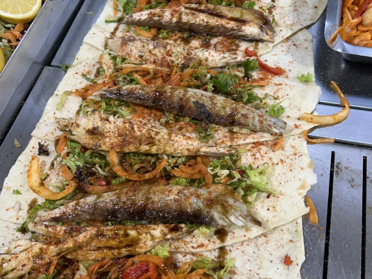 Grilled fish laid out on lavash with salad, onions and a dusting of pul biber
