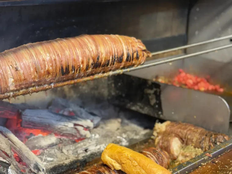 Kokoreç turning over the charcoal at a street grill