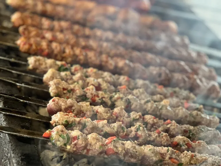 Skewers grilling over coals with bread warming beside them