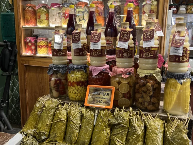 Jars of pickles and bundles of stuffed vine leaves in a shop window