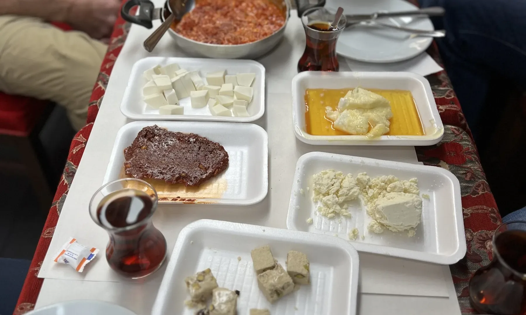 A long table laid with a Turkish breakfast: cheeses, olives, honey, kaymak, bread and tea