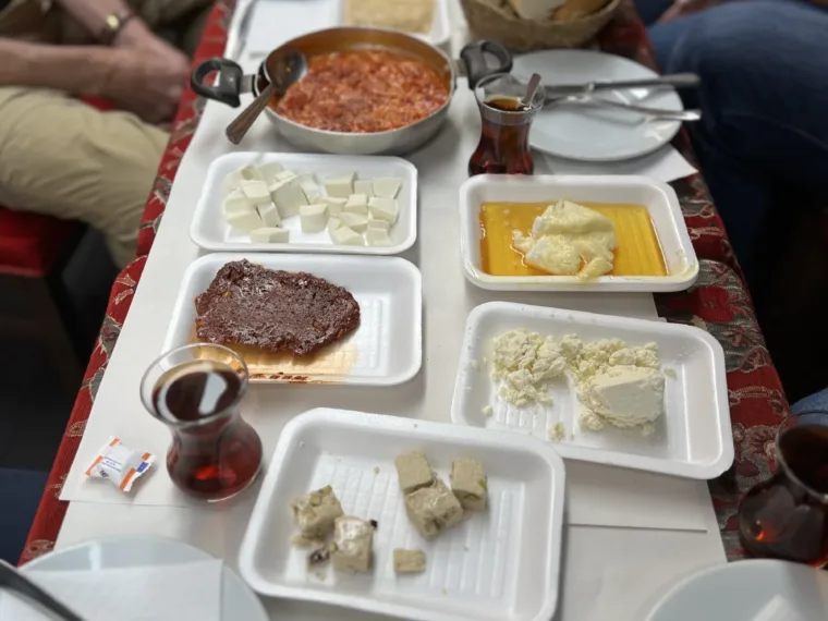 A long table laid with a Turkish breakfast: cheeses, olives, honey, kaymak, bread and tea