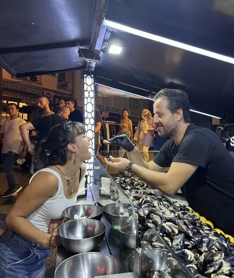 A midye dolma stall lit up at night with guests eating at the counter