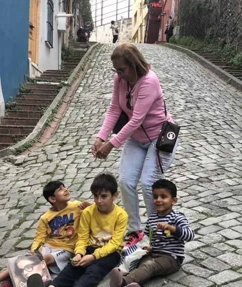 Children sitting on the cobbles of a Fener street while a visitor walks up the hill