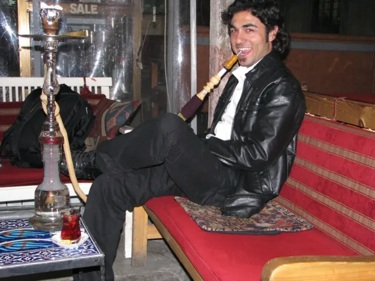 A man smoking a nargile water pipe on a bench