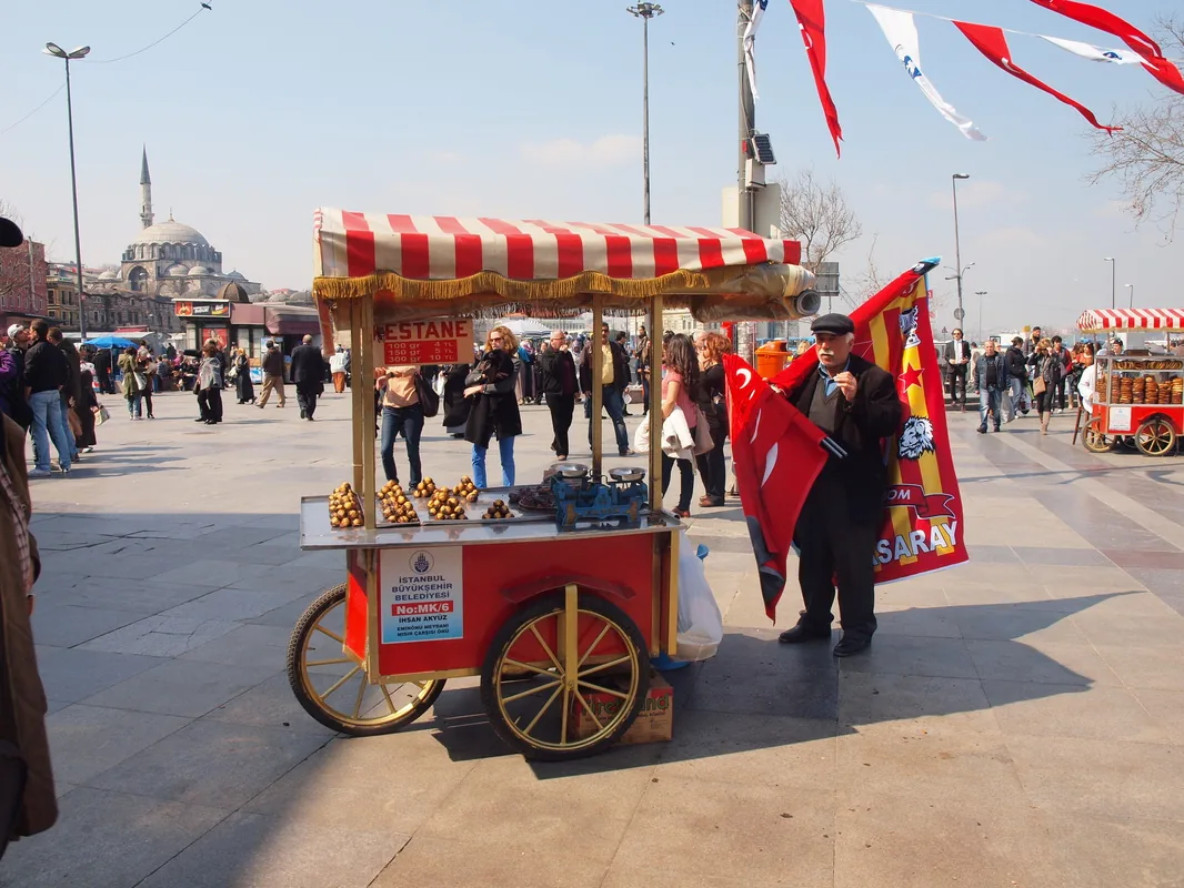 A red simit cart on a square in front of an Ottoman mosque