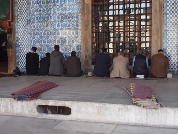 Worshippers sitting on the floor inside a tiled Istanbul mosque