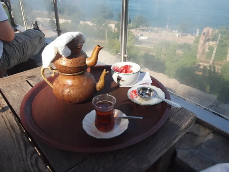 A copper teapot and a tulip glass of Turkish tea on a tray