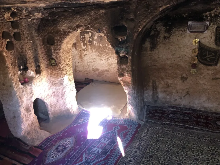 Carpets laid out inside a cave dwelling in southeastern Turkey, lit by the entrance