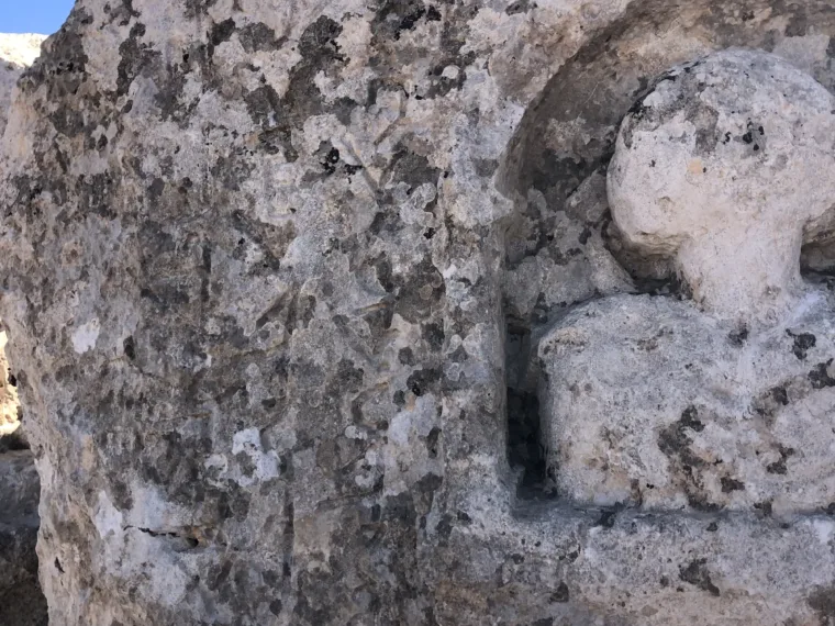 A worn figure carved in relief into a niche in the rock face