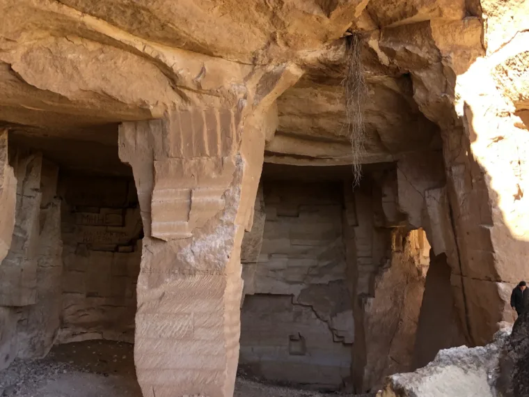A rock cut chamber with a visitor standing at the entrance for scale