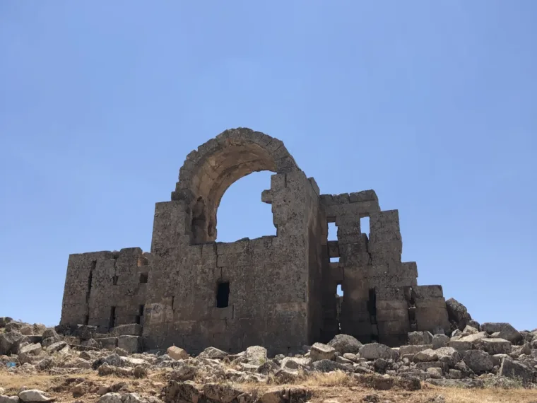 The arched wall of a ruined church standing alone against the sky