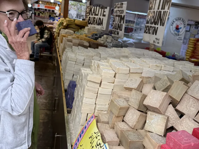 A guest tasting boza beside a market stall stacked with white and pink blocks in Istanbul