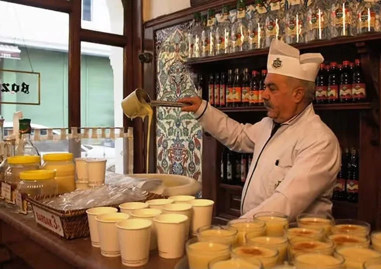 The boza maker pouring boza into a cup at an old Istanbul boza shop, on the Istanbul Off the Beaten Path tour