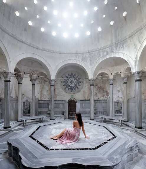 The domed marble hall of a historic Istanbul hammam, lit by the star shaped openings above